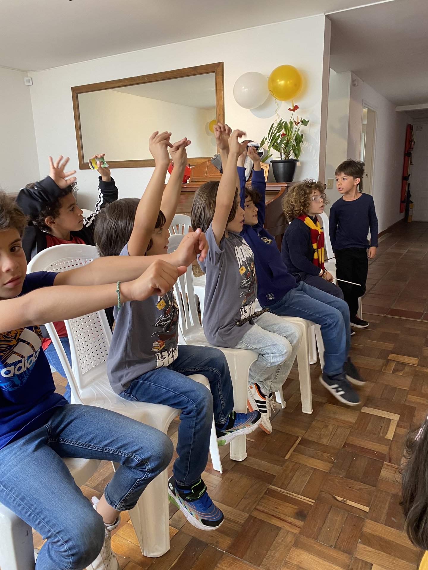 Niños emocionados levantando la mano durante un show de magia en casa